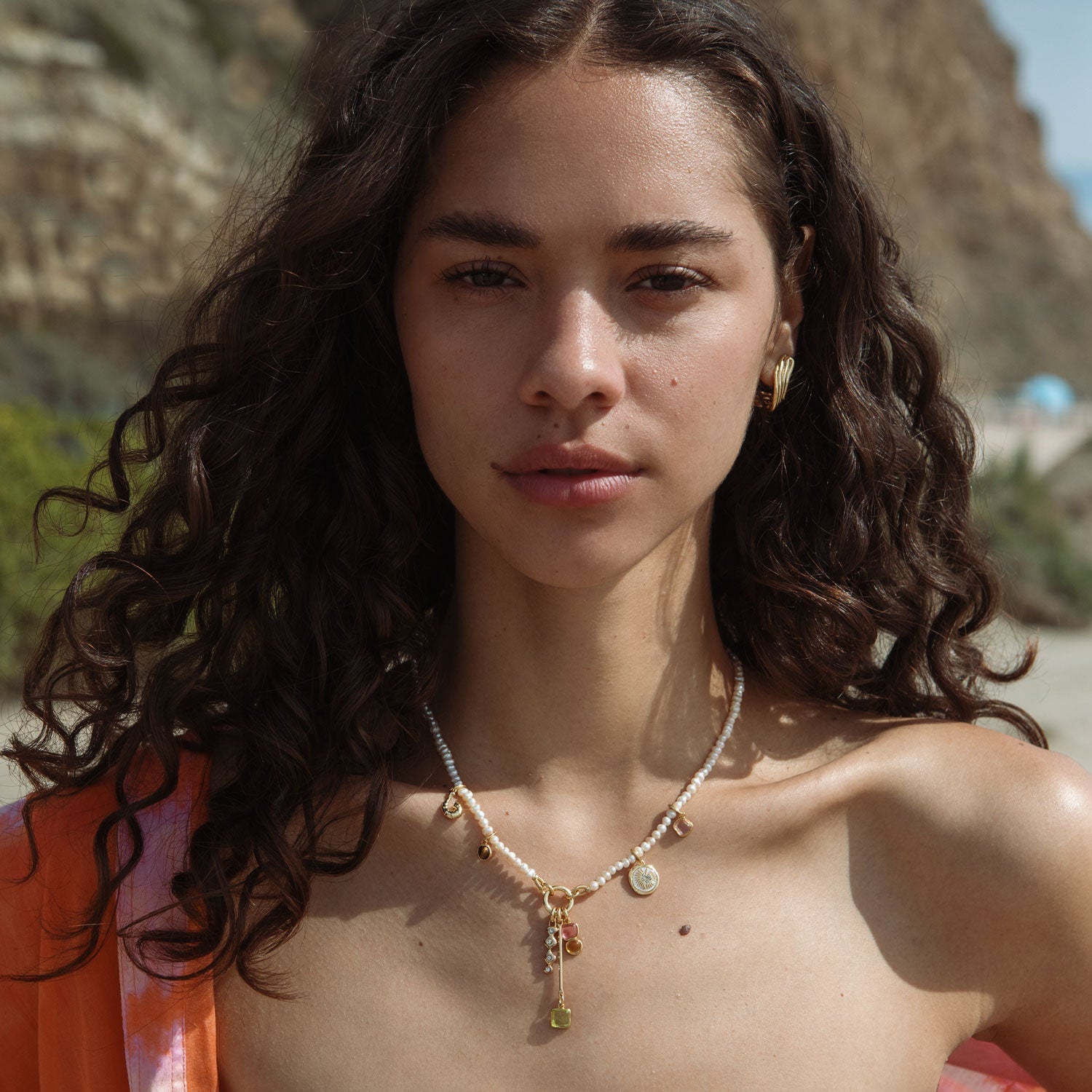 Woman with a necklace standing outdoors with mountains in the background