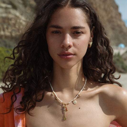 Woman with a necklace standing outdoors with mountains in the background
